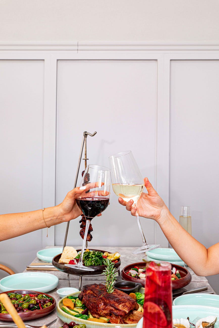 people holding clear wine glasses with red and white wine